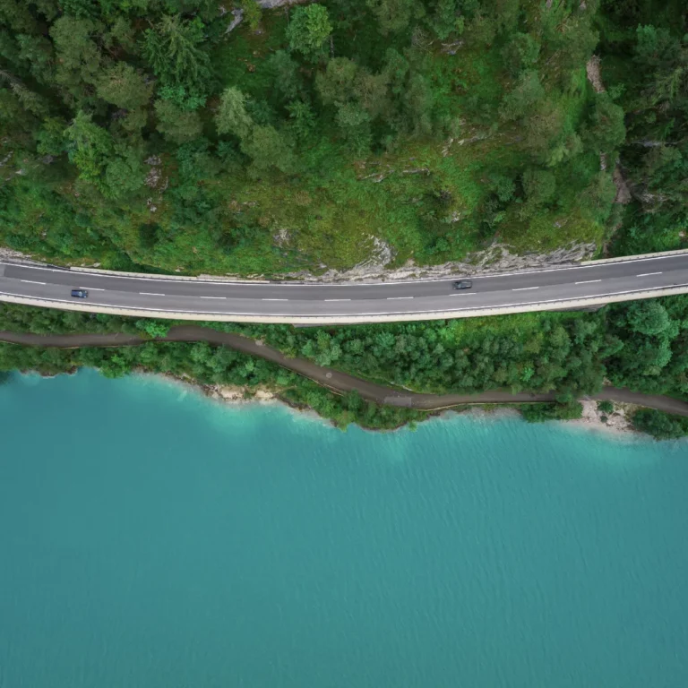 Blue water with green bank and a curvy road and forest illustrating TCFD reporting consulting